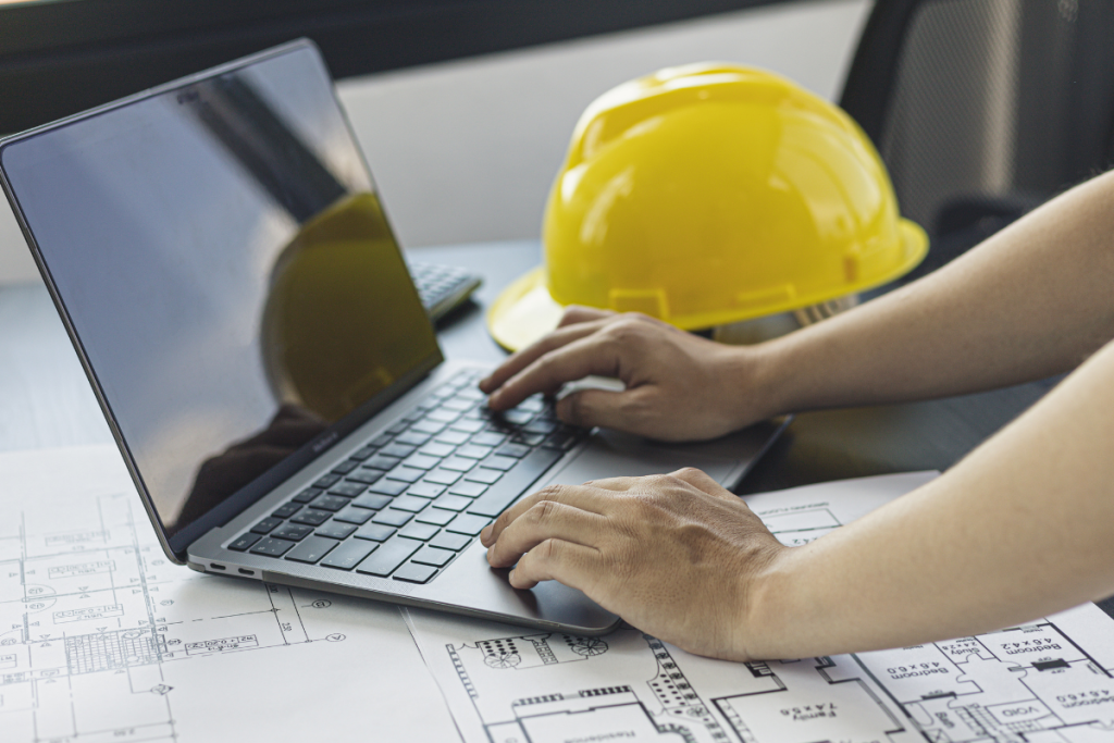 Independent contractor managing bookkeeping on a laptop at a construction site